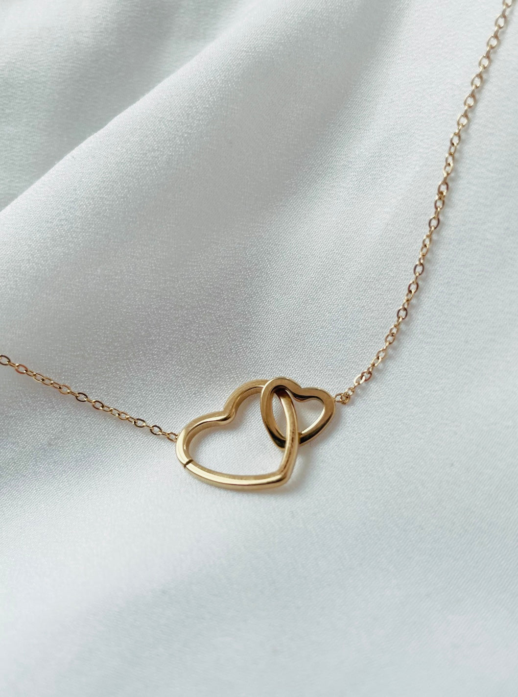 Edelstahlkette mit zwei verbundenen Herzen. Ein größeres und ein Kleiners Herz sind in einander gehangen und an eine feine Gliederkette angebracht.