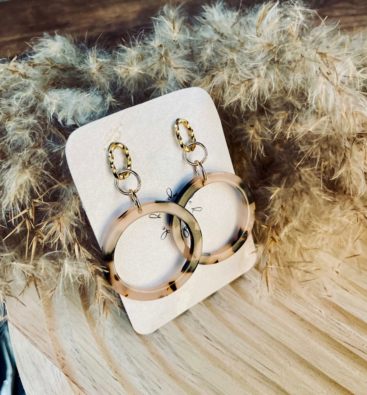 Ohrringe mit gedrehten goldenem Edelstahl Stecker und einem Acetat Ring mit beige schwarzem Muster.