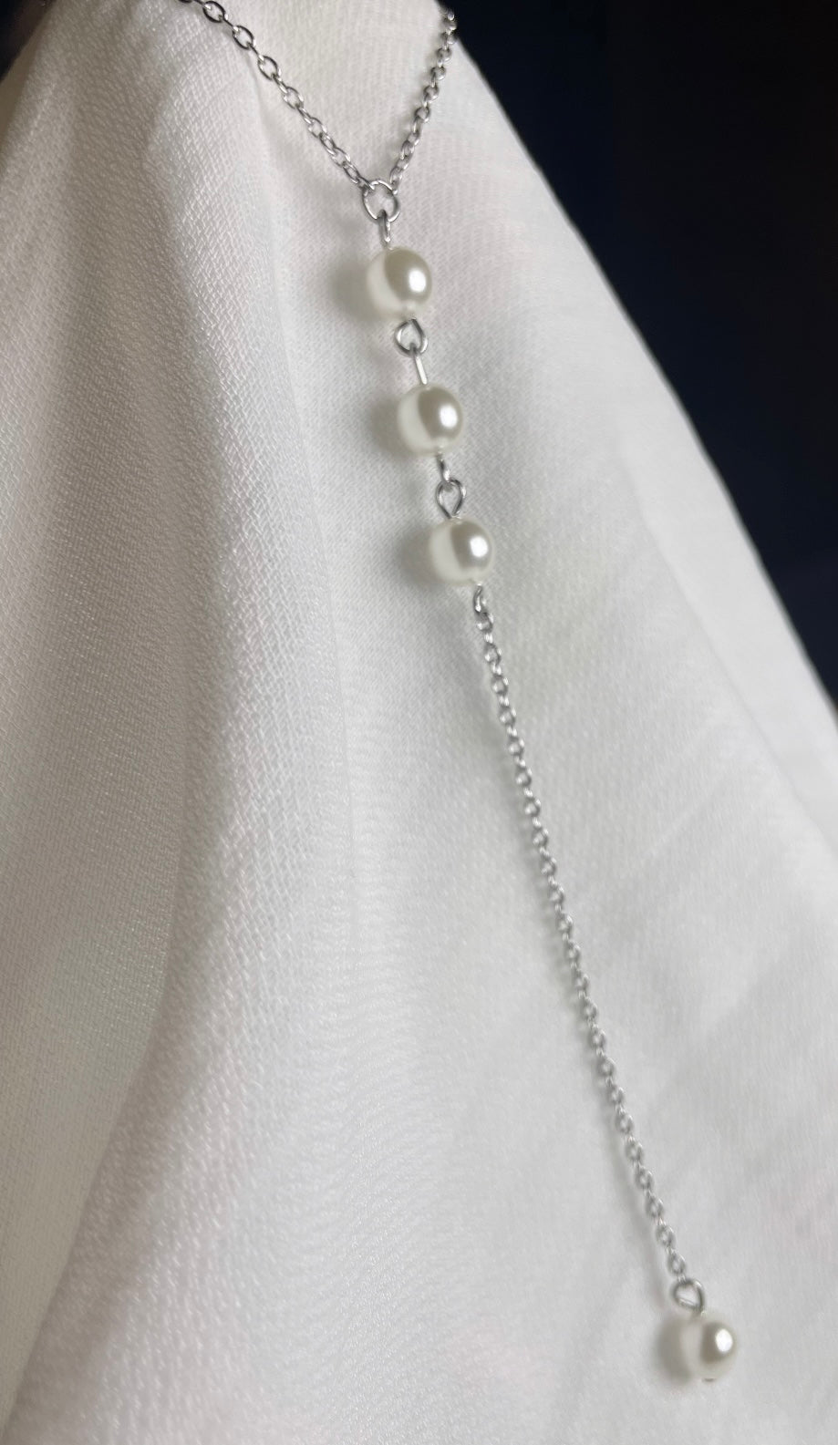 Silberne Rücken Halskette aus einer feinen Gliederkette mit einer Perle vorne. Im Rückenbereich ist sie hängend mit drei untereinander gereihten Perlen und einer Perle am Ende versehen.