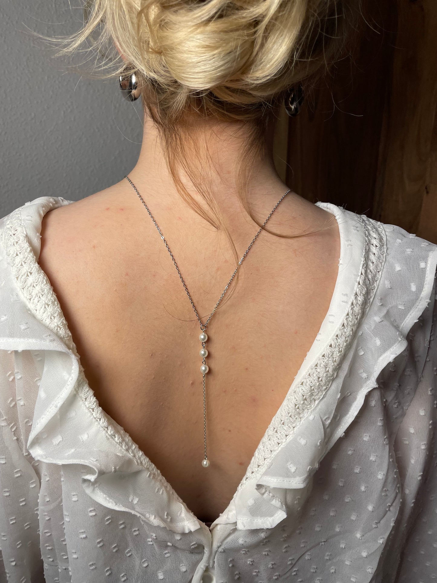 Silberne Rücken Halskette aus einer feinen Gliederkette mit einer Perle vorne. Im Rückenbereich ist sie hängend mit drei untereinander gereihten Perlen und einer Perle am Ende versehen.