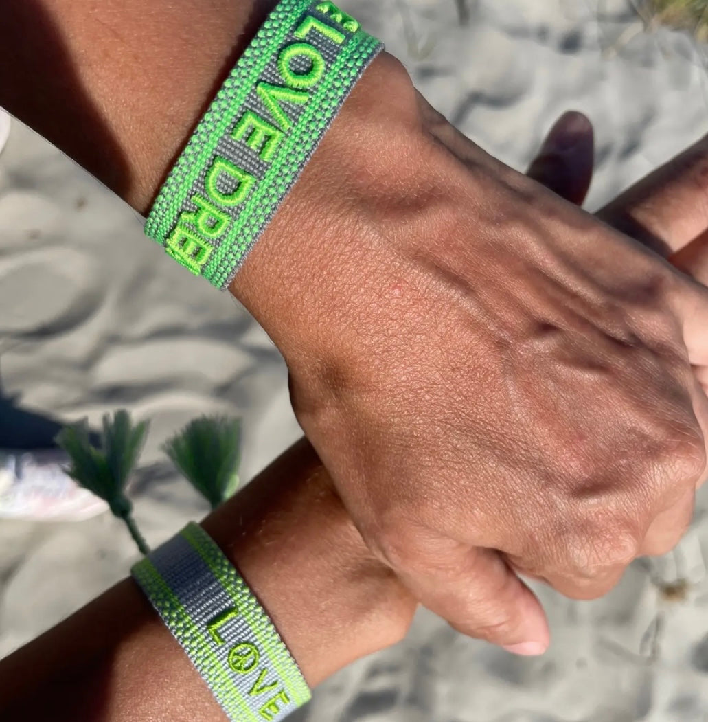 Statement Armband in grau mit Neon grünem Schriftzug "Smile Love Dream". Über Schiebeknoten verstellbar.