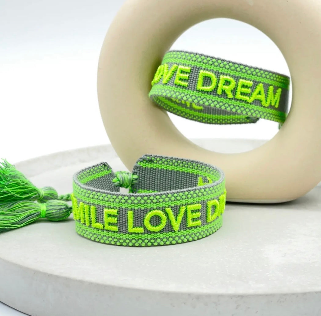 Statement Armband in grau mit Neon grünem Schriftzug "Smile Love Dream". Über Schiebeknoten verstellbar.