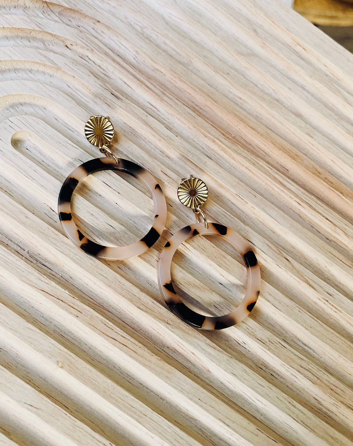 Ohrringe mit goldenem Edelstahl Stecker und einem Acetat Ring mit beige schwarzem Muster.