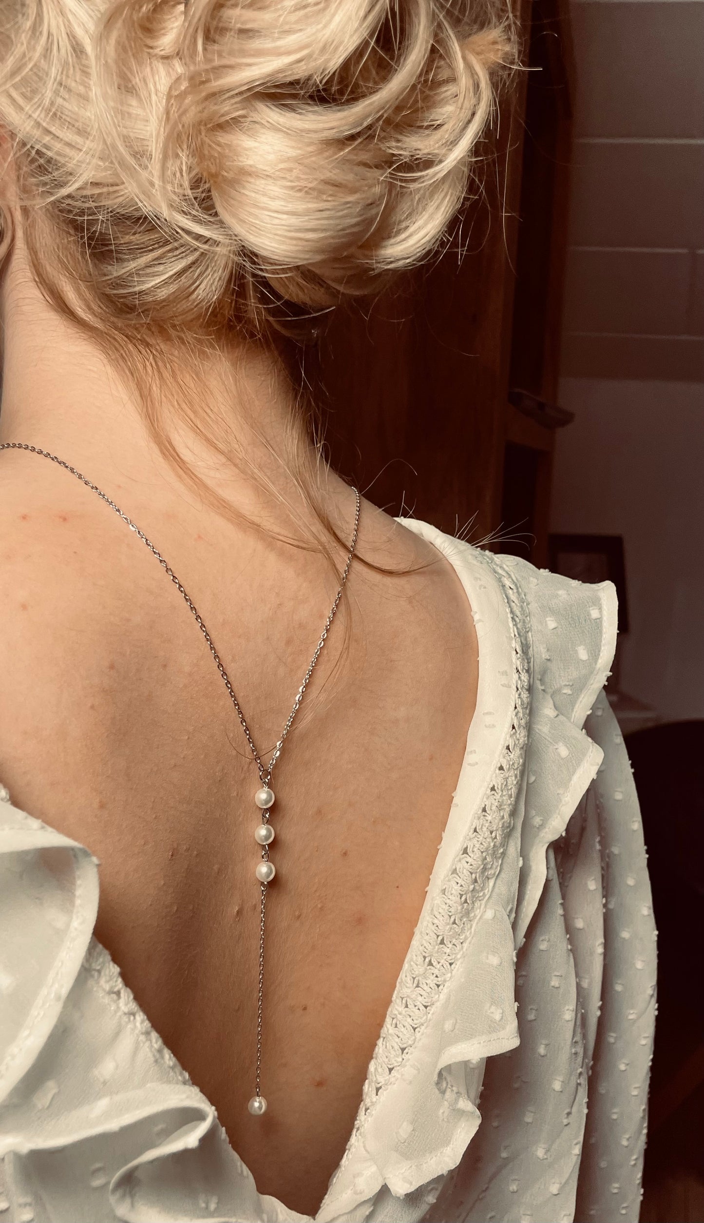 Silberne Rücken Halskette aus einer feinen Gliederkette mit einer Perle vorne. Im Rückenbereich ist sie hängend mit drei untereinander gereihten Perlen und einer Perle am Ende versehen.
