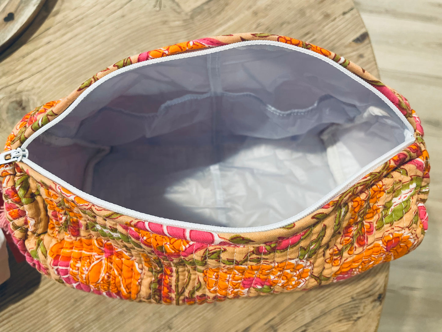 Praktische knallig orange Kulturtasche im Ripp-Design mit pinken Blumen. Innen mit einem wasserfesten Bezug und zwei kleinen Fächern!