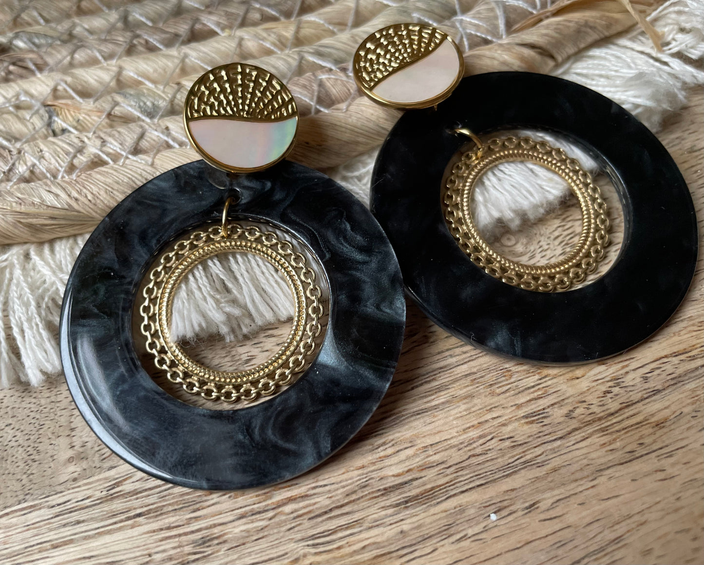 Edelstahl Ohrringe mit schwarz melierten Scheiben Anhänger in den ein goldener Boho Ring eingehängt ist.