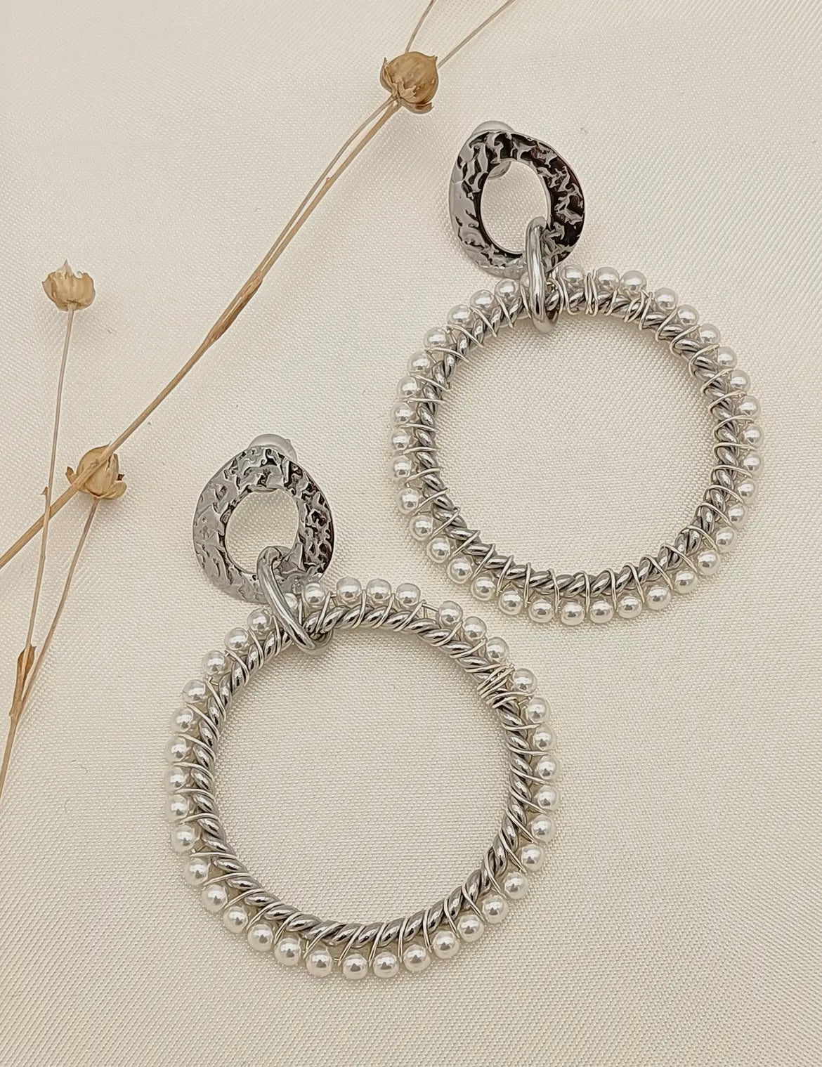 Große, runde silber Ohrringe, die umgeben sind von kleinen weißen Perlen. Der Stecker ist oval aus einem gehämmerten gearbeitet