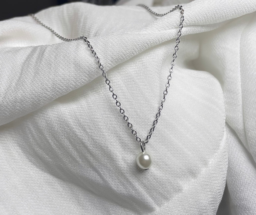 Silberne Rücken Halskette aus einer feinen Gliederkette mit einer Perle vorne. Im Rückenbereich ist sie hängend mit drei untereinander gereihten Perlen und einer Perle am Ende versehen.