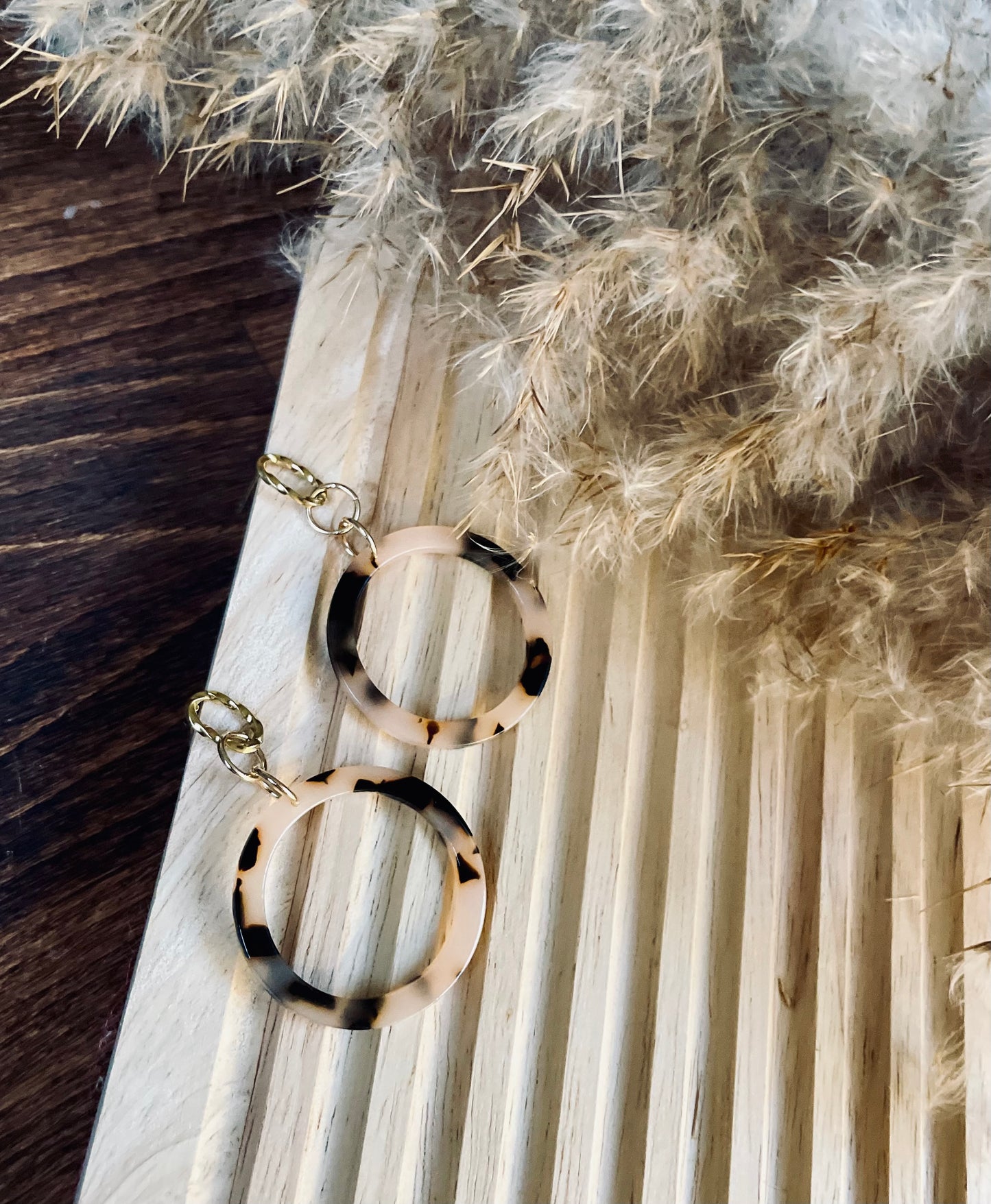 Ohrringe mit gedrehten goldenem Edelstahl Stecker und einem Acetat Ring mit beige schwarzem Muster.