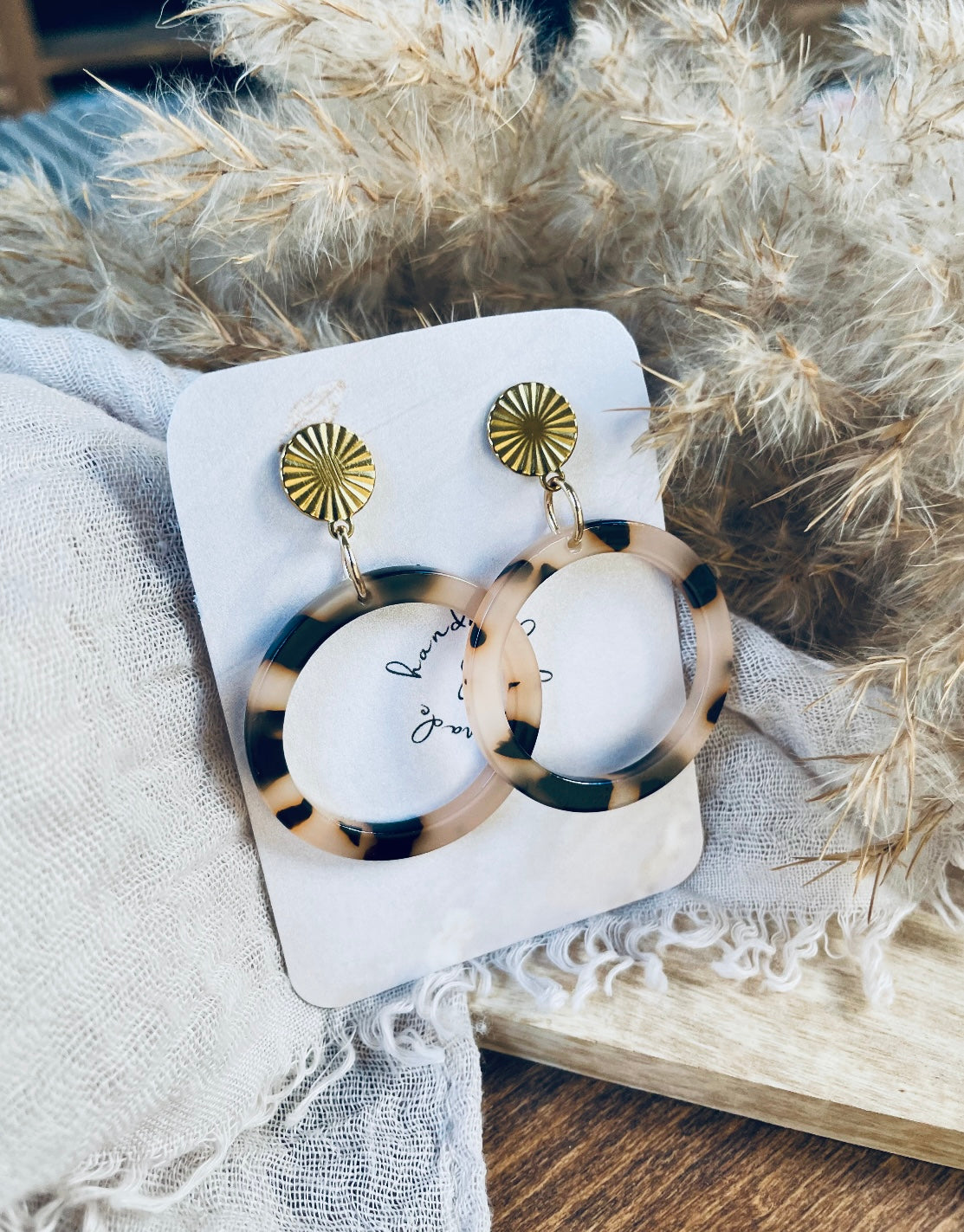 Ohrringe mit goldenem Edelstahl Stecker und einem Acetat Ring mit beige schwarzem Muster.