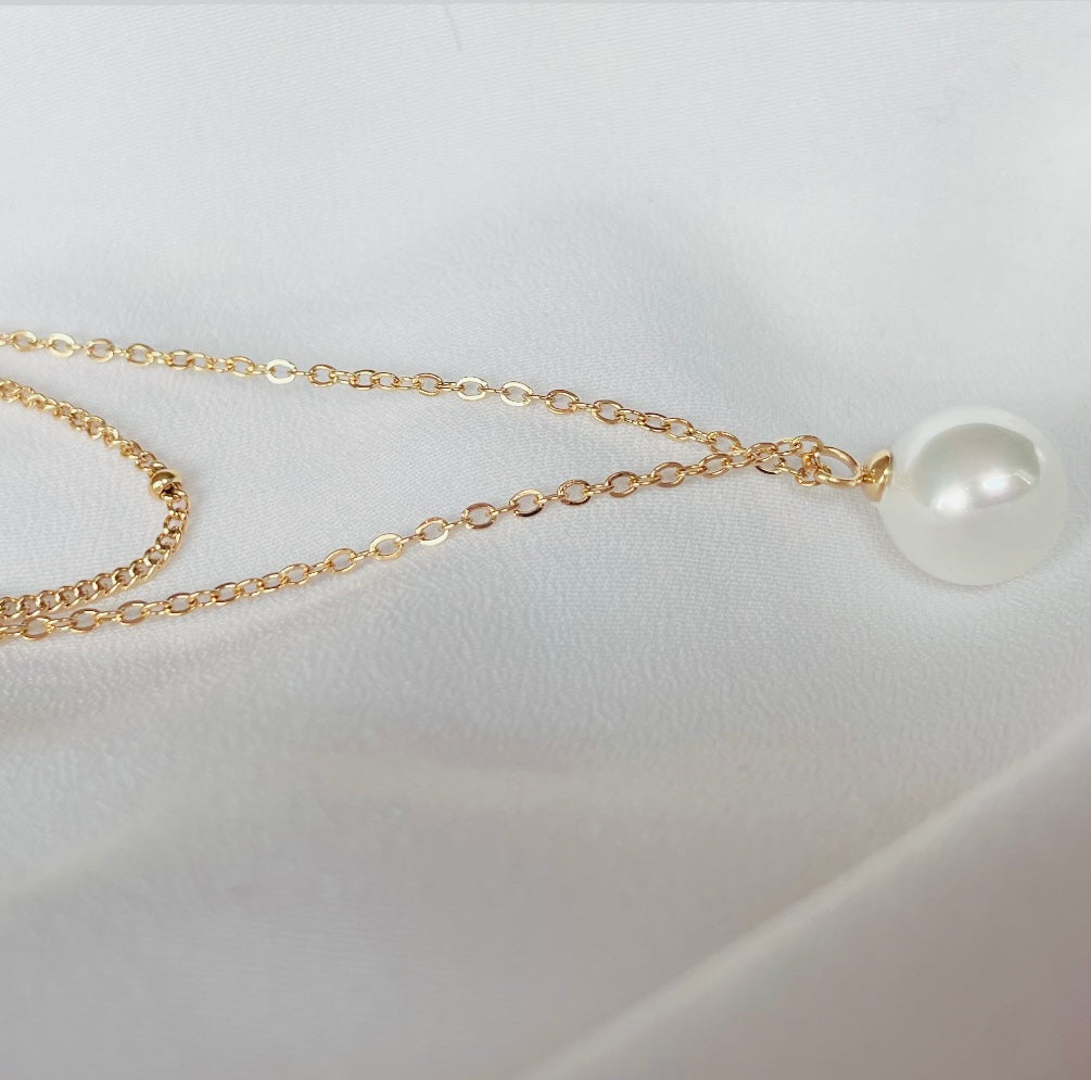 Zweireihige goldene Edelstahlkette mit einer filigranen Gliederkette mit kleinen Edelstahlkügelchen und einer feinen Gliederkette mit eingefassten Perlenanhänger.