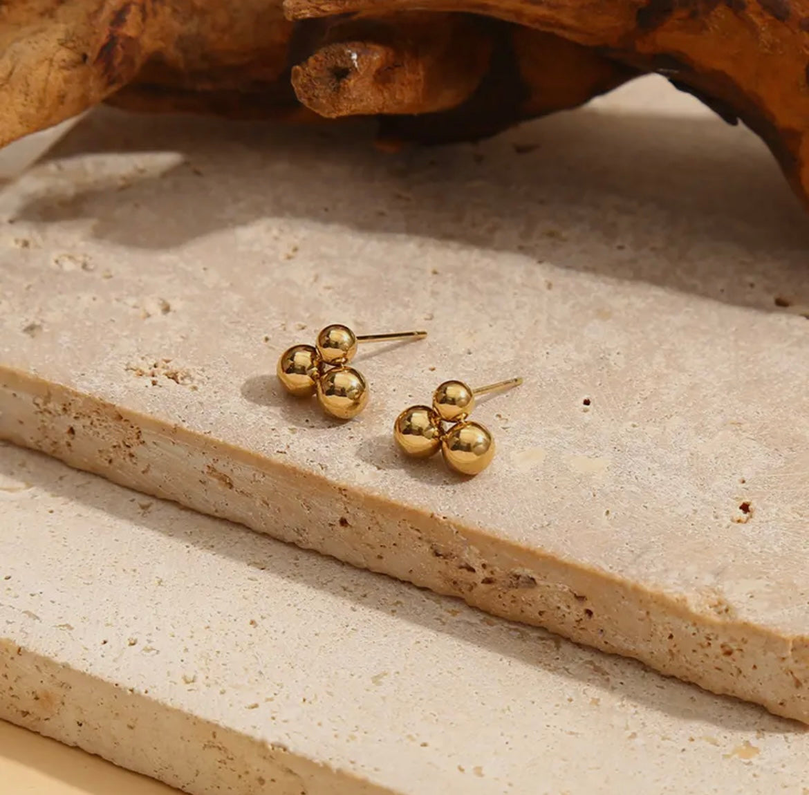 Ohrstecker sind aus glänzendem Edelstahl in gold gefertigt aus drei Kugeln zu einem Dreieck aneinander gesetzt.