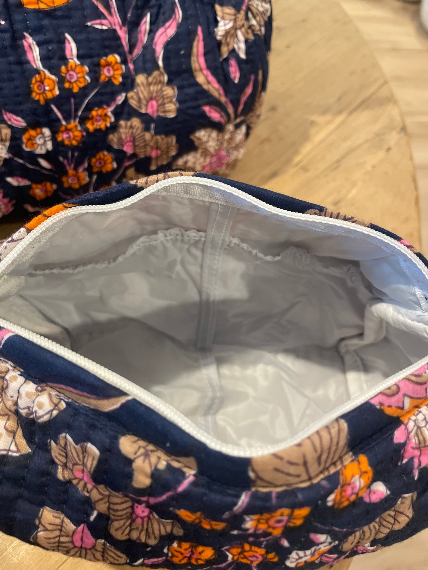 Praktische blaue Kulturtasche im Ripp-Design mit rosa Blumen und beigen Ranken. Innen mit einem wasserfesten Bezug und zwei kleinen Fächern!