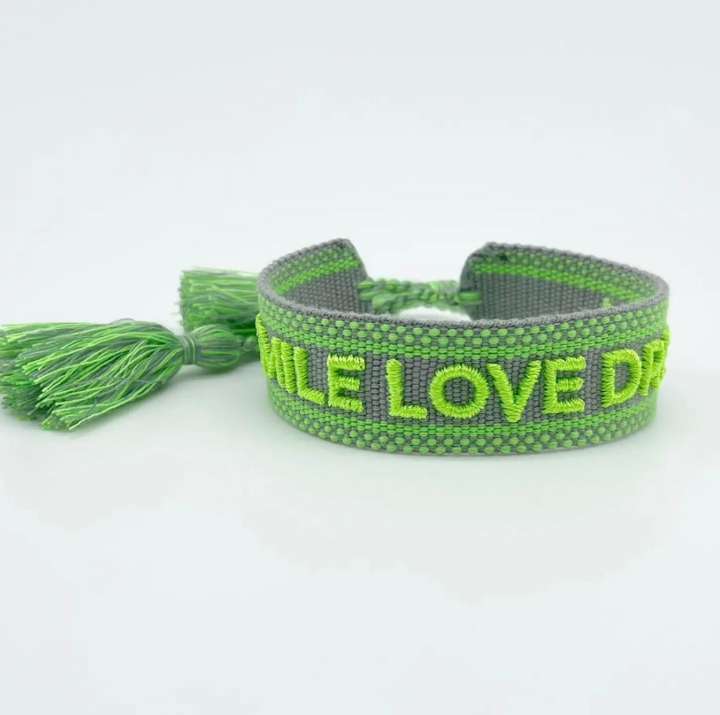 Statement Armband in grau mit Neon grünem Schriftzug "Smile Love Dream". Über Schiebeknoten verstellbar.