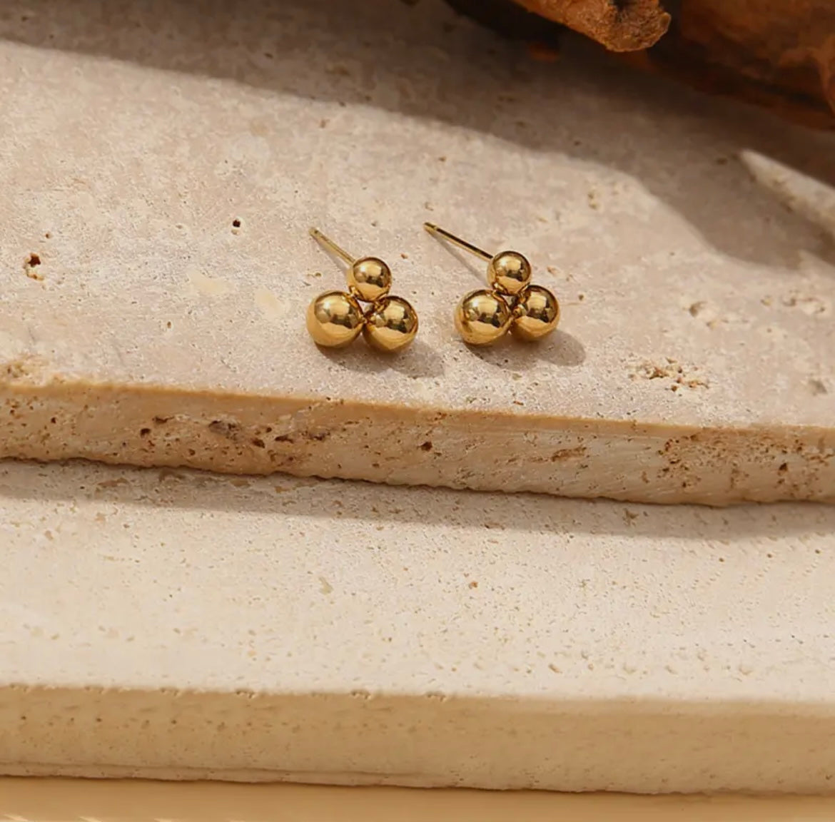 Ohrstecker sind aus glänzendem Edelstahl in gold gefertigt aus drei Kugeln zu einem Dreieck aneinander gesetzt.