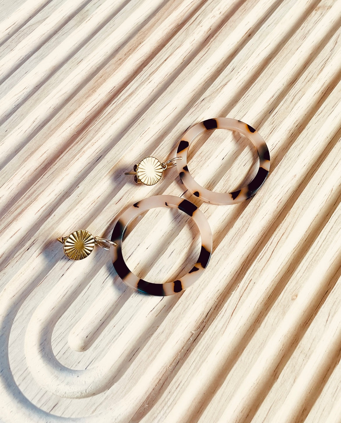 Ohrringe mit goldenem Edelstahl Stecker und einem Acetat Ring mit beige schwarzem Muster.