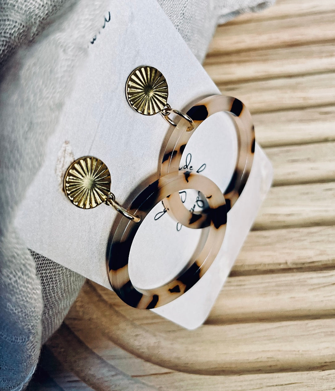 Ohrringe mit goldenem Edelstahl Stecker und einem Acetat Ring mit beige schwarzem Muster.