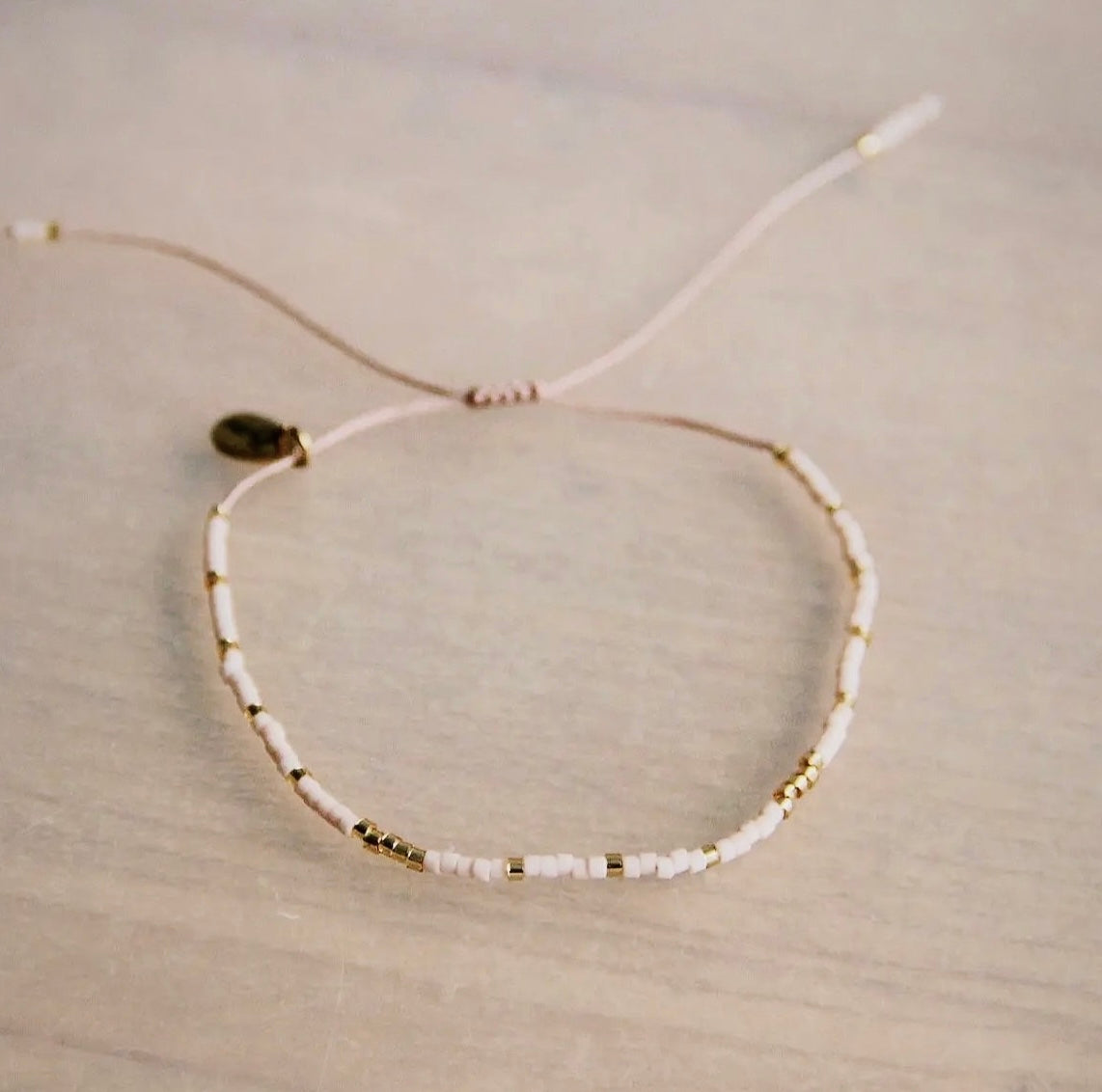 Perlen Armband in der Farbe nude/ gold. Durch den Schiebeknoten ist es variabel verstellbar. In filigraner Handarbeit hergestellt mit Miyuki Perlen.