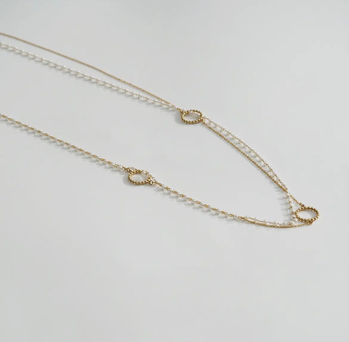 Lange goldene zweireihige Edelstahl Kette. Mit einer Gliederkette und eine Kette mit kleinen weißen Perlchen.