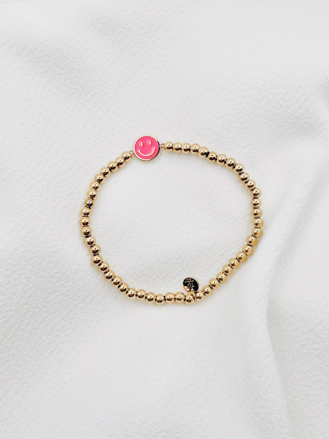 Armband mit goldenen Edelstahlkügelchen und pinken Smiley Anhänger. 