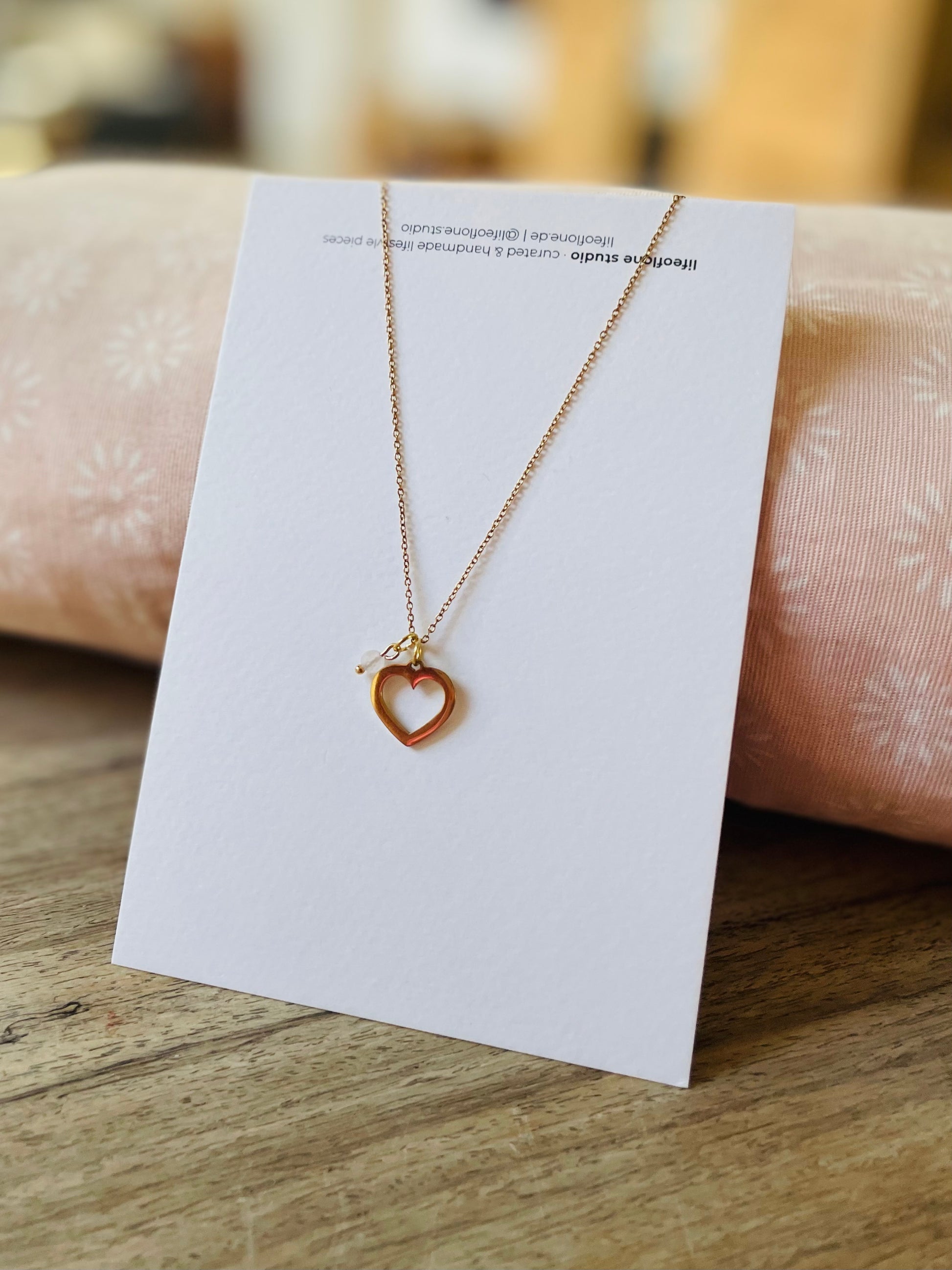 Feine Halskette aus Edelstahl mit hübschem Herz und Steinchen Anhänger! Der Anhänger besteht aus einem goldenen offenen Edelstahl Herz und kleinem Rosenquarz Anhänger.