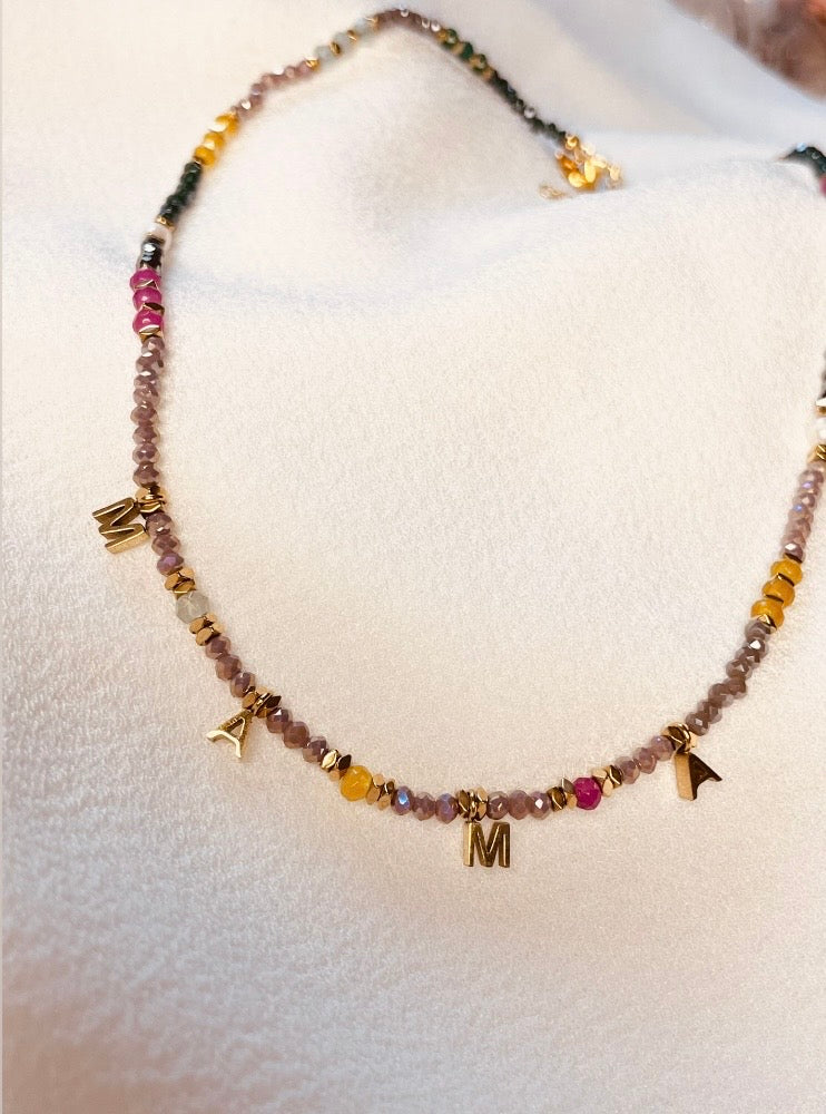 Feine Perlenkette mit Miyuki Perlen im glänzenden Facettenschliff und goldenen Edelstahlkügelchen ab. Auch zwei weiße Kunstperlen zieren die Kette. In der Mitte sind die Buchstaben "MAMA" in goldenem PEdelstahl eingehängt.
