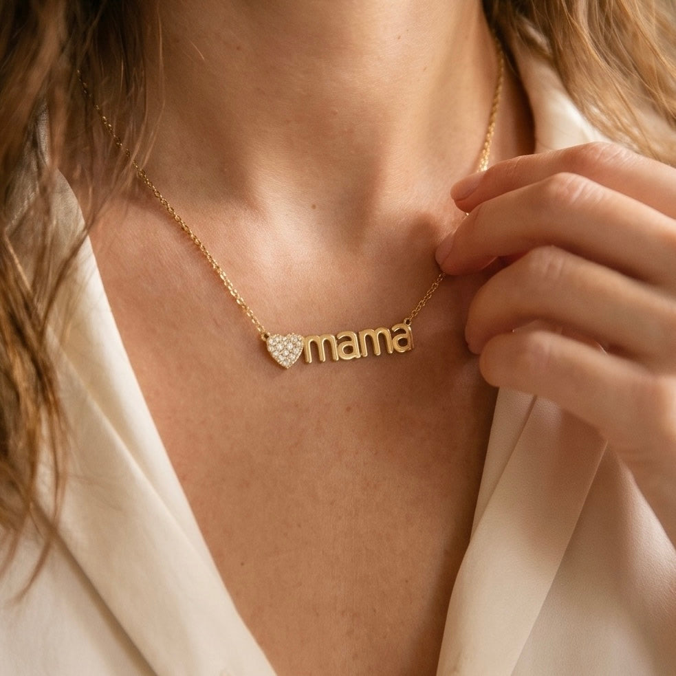 Feine goldene Edelstahl Kette  aus einer feinen Gliederkette mit einem Verlängerungskettchen. In der Mitte ist ein goldenes Herzchen mit kleinen Zirkoniasteinchen und dem Schruftzug „MAMA“ eingearbeitet.