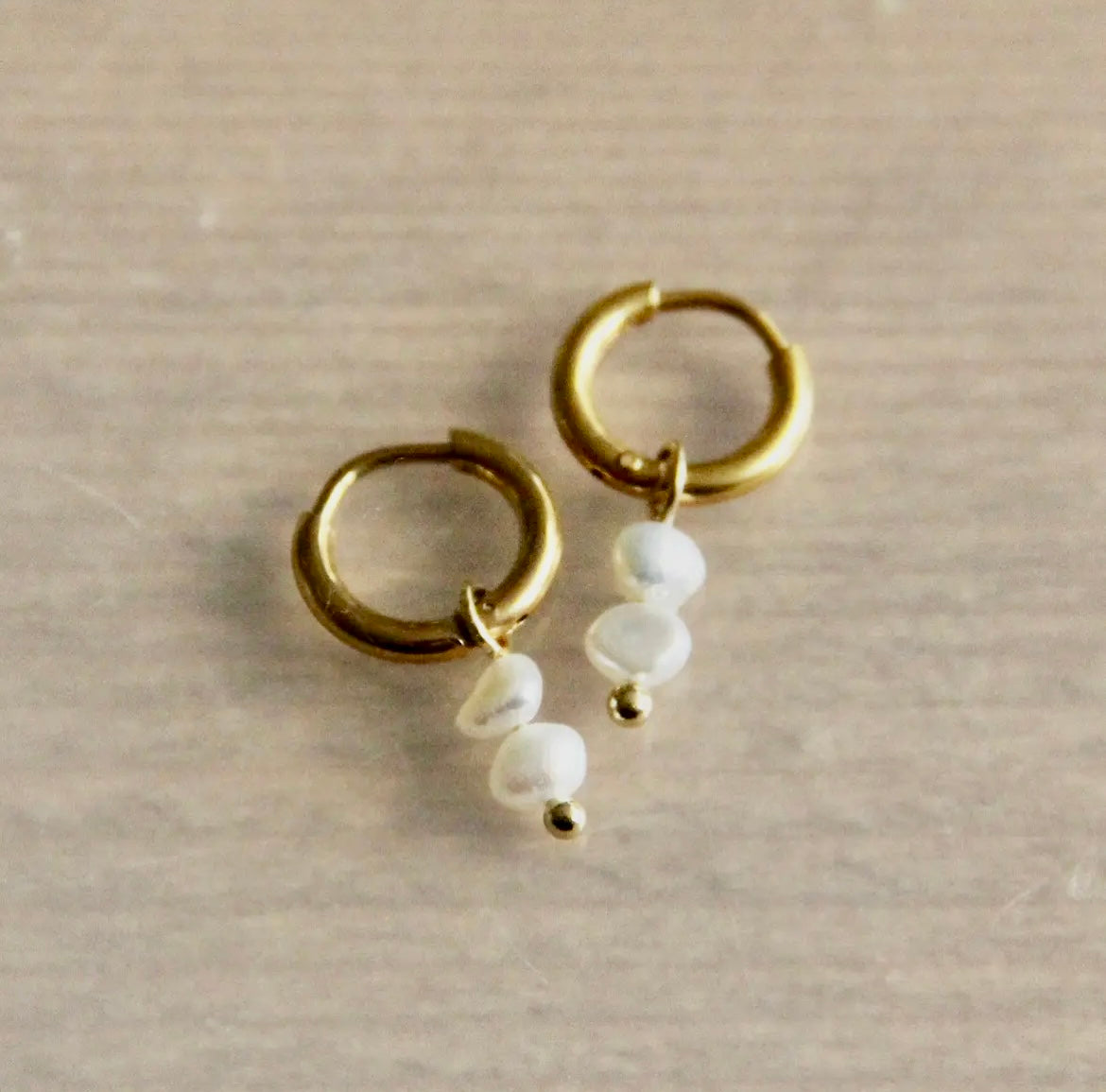 Goldene Ohrringe mit zwei kleinen Süsswasserperlen. Diese Creolen mit klassischen chic haben zwei weiße Perlen. 