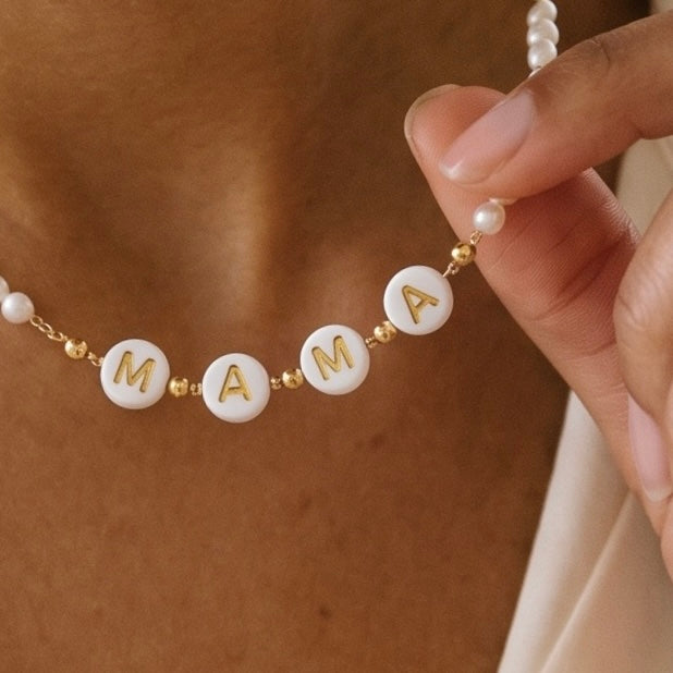 Hübsche zarte Perlenkette mit weißen Kunstperlchen und in der Mitte die Buchstaben: "MAMA" in weiß gold. 