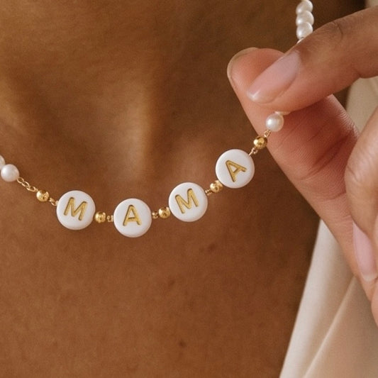 Hübsche zarte Perlenkette mit weißen Kunstperlchen und in der Mitte die Buchstaben: "MAMA" in weiß gold. 