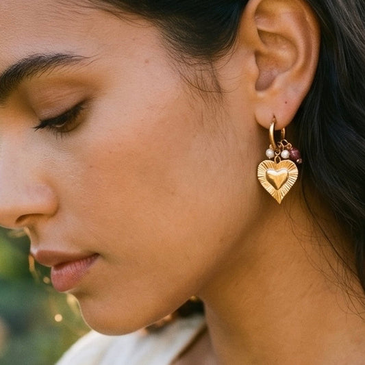 Goldene Edelstahl Creole ist ein Herz ein- gehangen und ein Anhänger mit Strasssteinchen Perlchen und Facetten eingehangen.