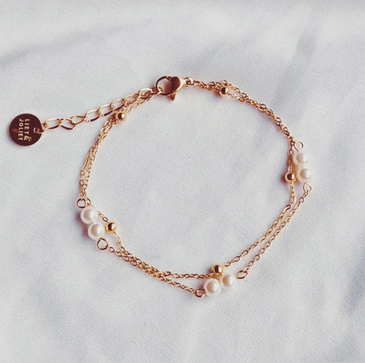 Filigranes Edelstahl Armband in Gold, aus zwei Reihen von Gliedeketten mit weißen Perlen und kleinen Edelstahlkügelchen.