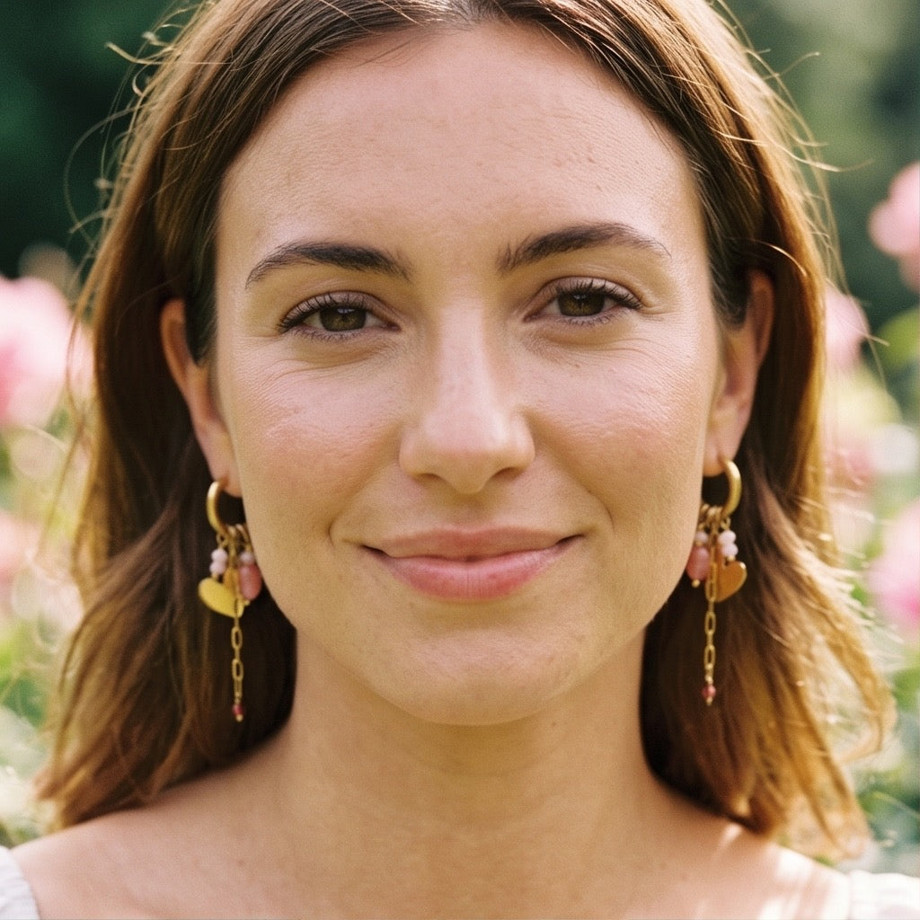 In goldene Click Creole ist ein gedrehter Ring eingehangen mit poliertem Herzchen. Zudem sind weitere kleine rosa Steinchen eingehangen und ein kleines Edelstahlkettchen