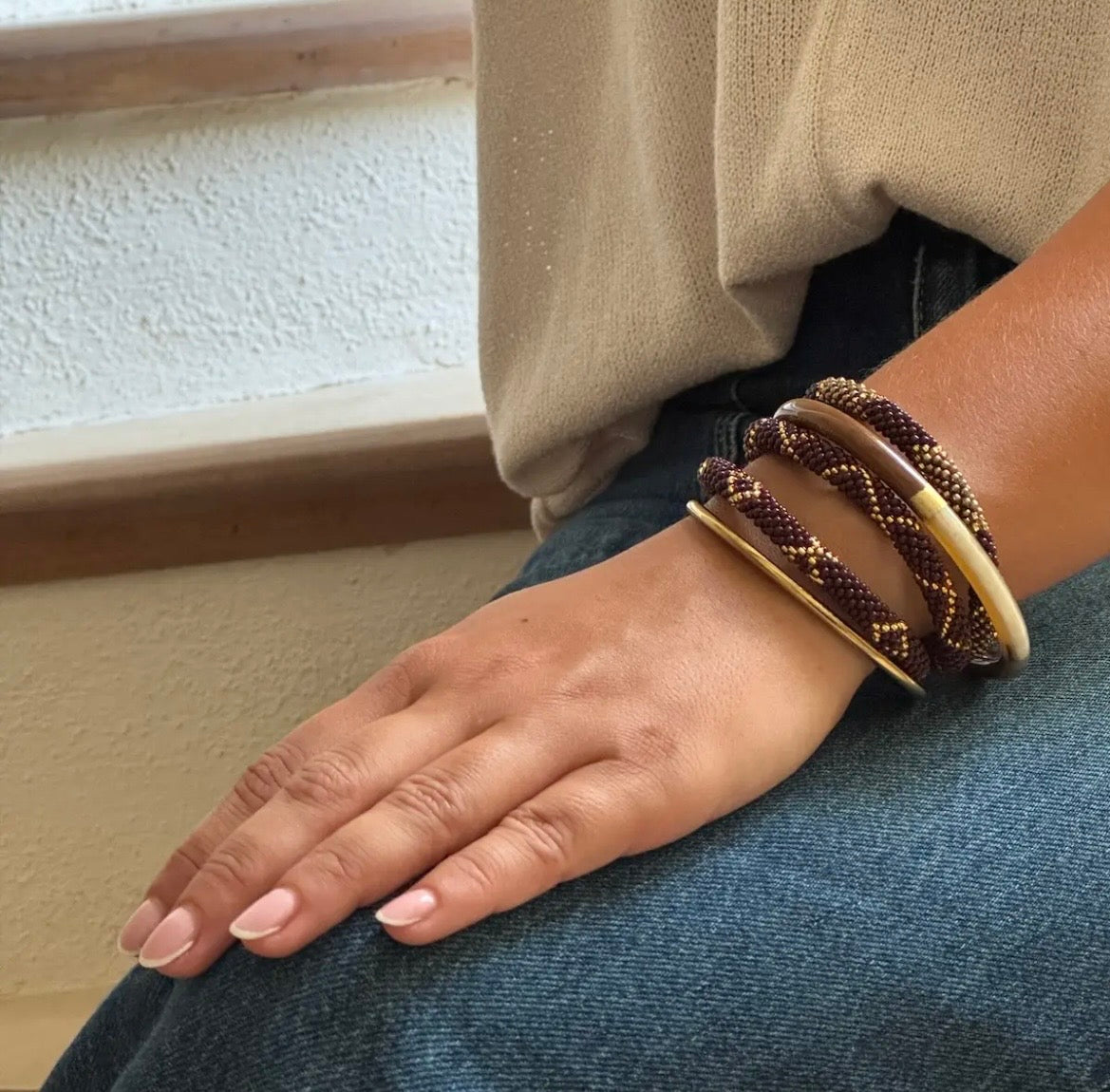 Handgefertigtes Boho-Armband aus Glasperlen in Braun und Gold am Handgelenk getragen