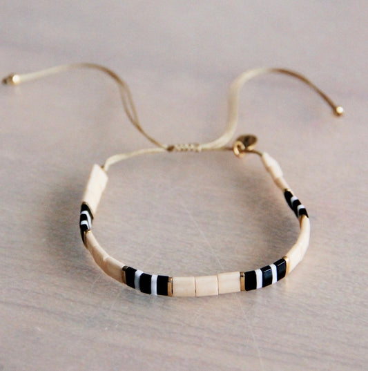 Hübsches gewebtes Armband in der Farbe nude, schwarz weiß und vergoldeten Perlen. Durch den Schiebeknoten ist es variabel verstellbar. Mit Tilabead Miyuki Perlen handgearbeitet.
