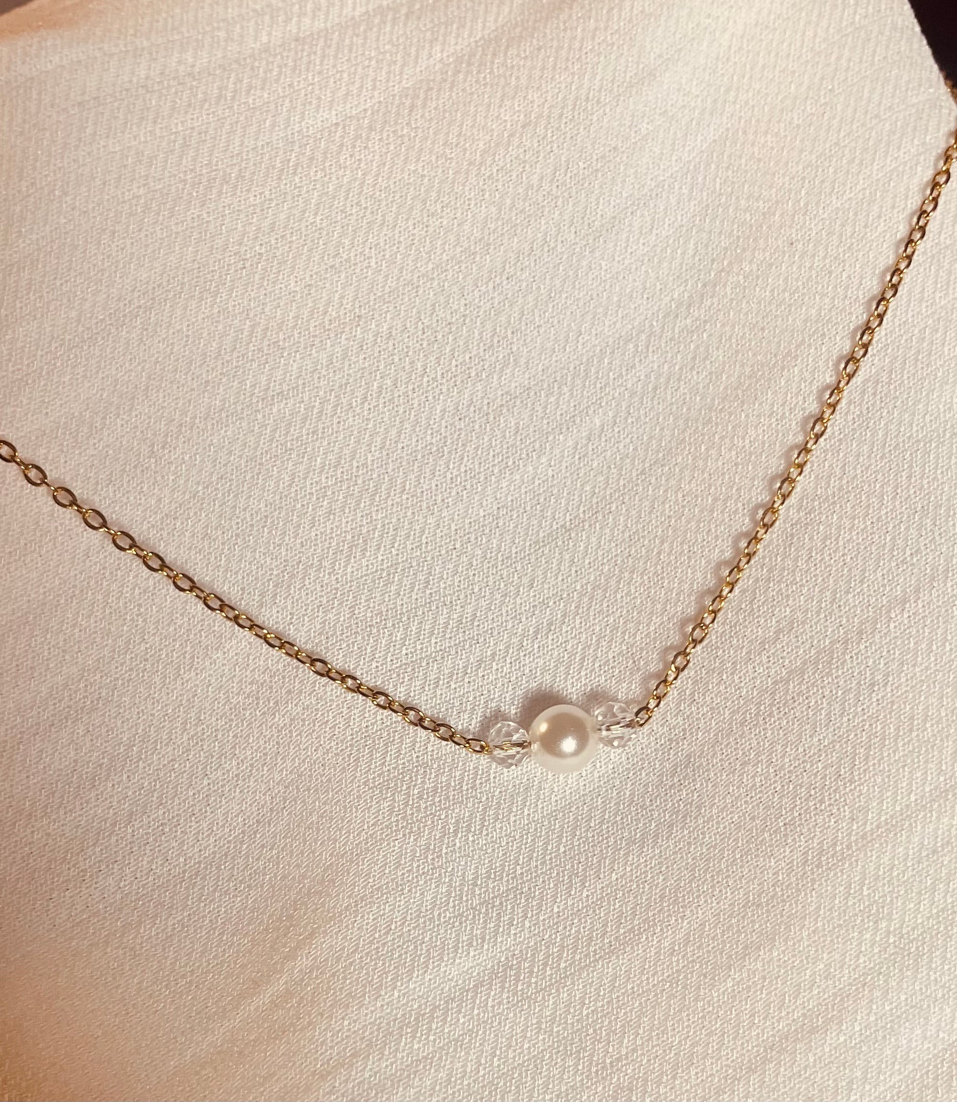 Rücken Halskette mit feiner Gliederkette mit einer Perle und zwei klaren Kristallperlen vorne. Im Rückenbereich mit drei unterschiedlich langen hängenden Gliederketten, am Ende mit je drei unterschiedlich großen Perlen! Rückenteil ist abnehmbar !