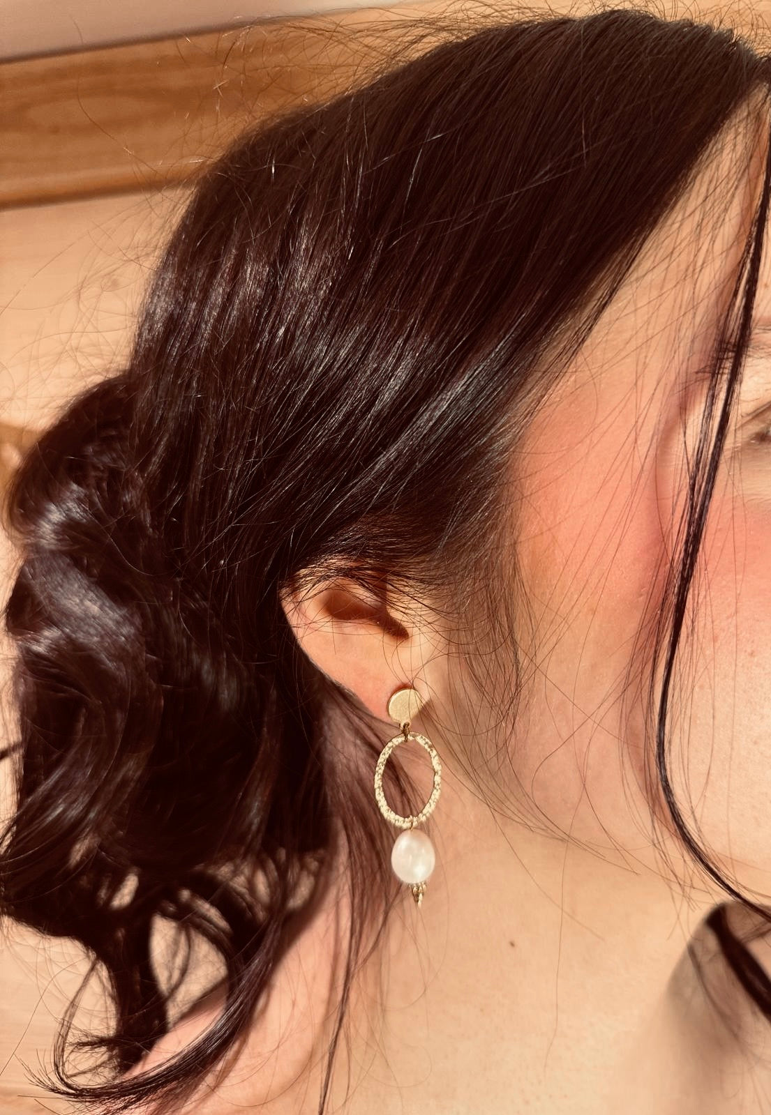 Edelstahl Ohrringe in Gold mit ovalem Anhänger mit gehämmerter Optik und ovaler weißer Perle hängend 