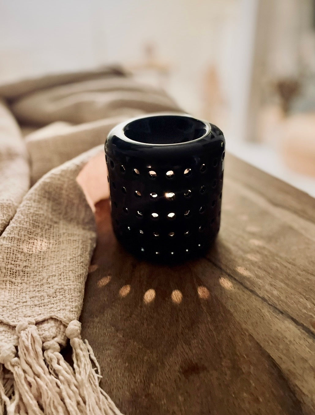 Schwarze Duftlampe Coliseo ist ein Hingucker. Durch die vielen Löcher entsteht ein tolles Lichtspiel. Die Öffnung oben ist groß genug, um einen großen Duftmelt