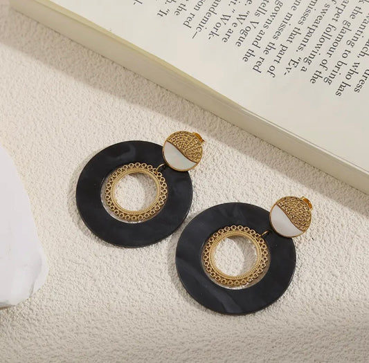 Edelstahl Ohrringe mit schwarz melierten Scheiben Anhänger in den ein goldener Boho Ring eingehängt ist.