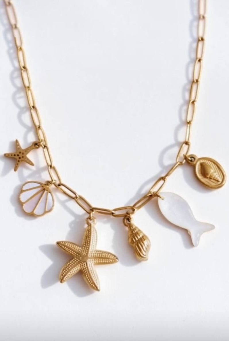 Charm Gliederkette aus Edelstahl in Gold mit länglichen Gliedern. Eingegangen sind sechs Charms im Meeres Design. Vier Muscheln, ein Seestern und ein Perlmutt Fisch. Wasserfest.  