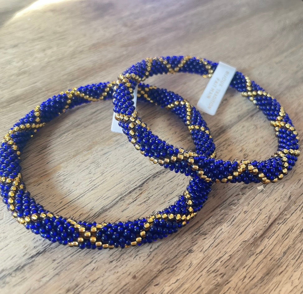 Glasperlen Armband blau mit goldenem Boho Muster. Liegend auf Holztisch.