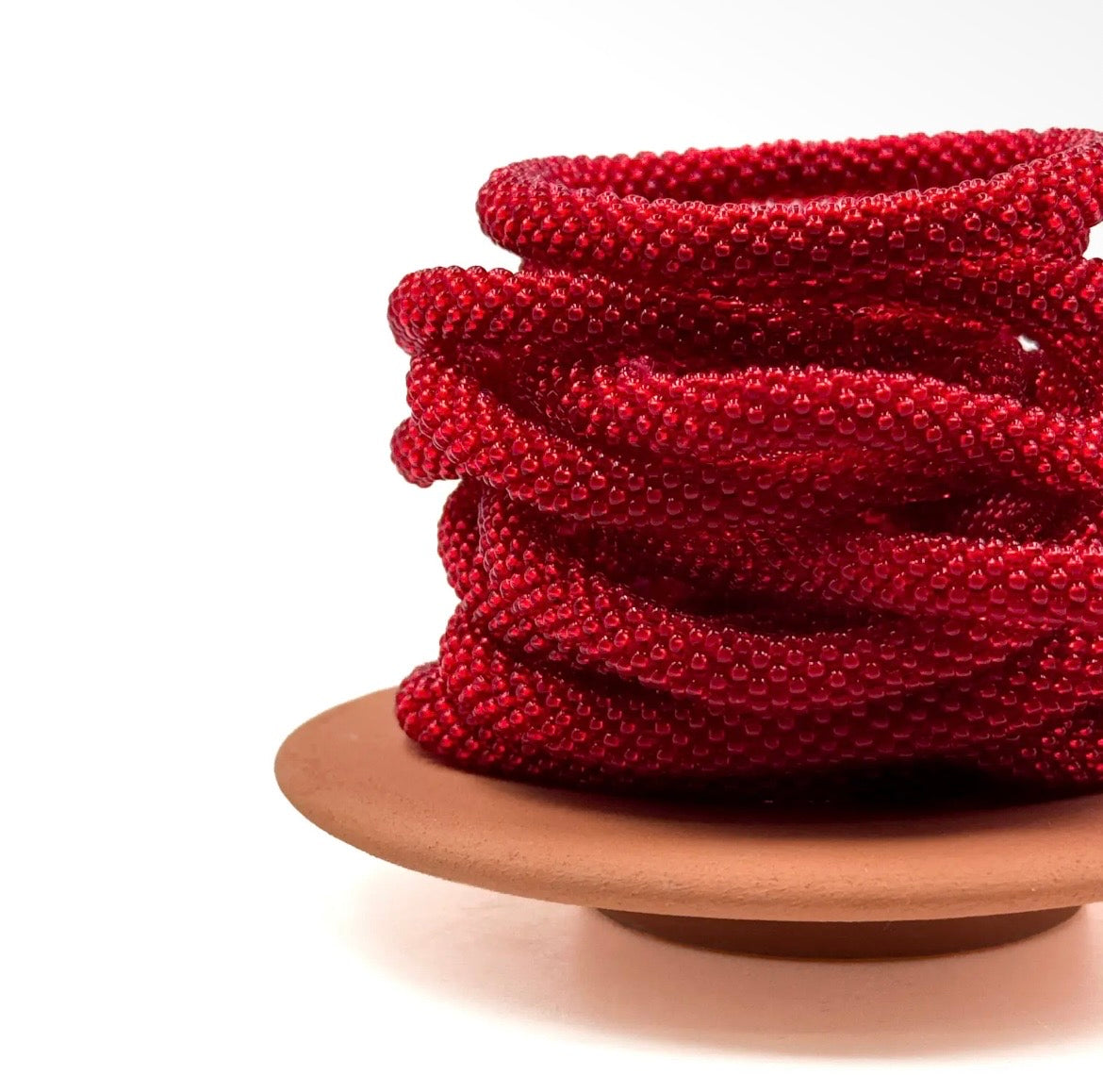 Nahaufnahme der Glasperlen Armbänder in knalligem rot, liegend auf Schale.
